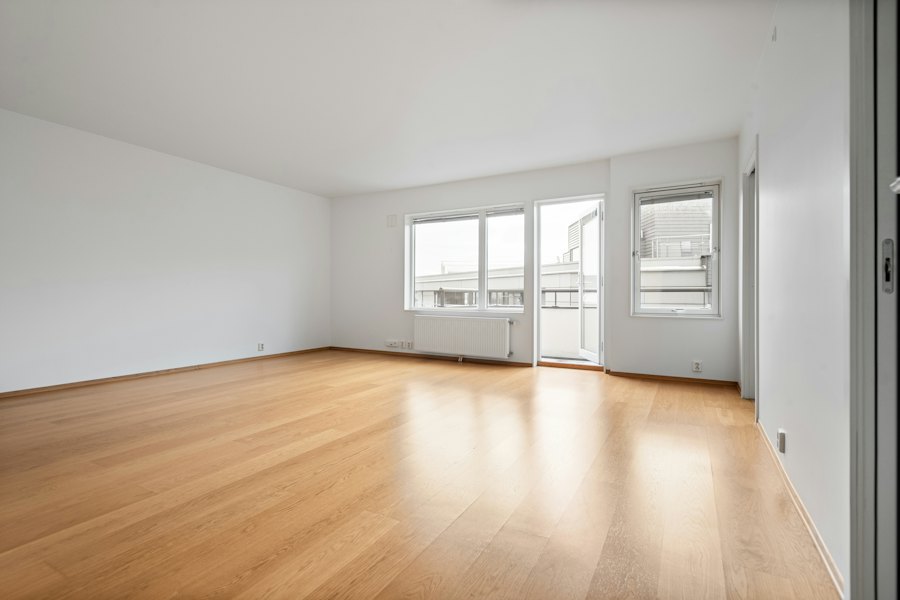 An empty room with hardwood floors and white walls